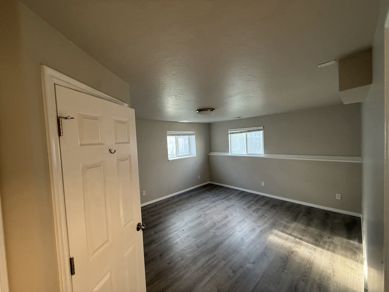 Empty basement room with freshly painted walls and white baseboards