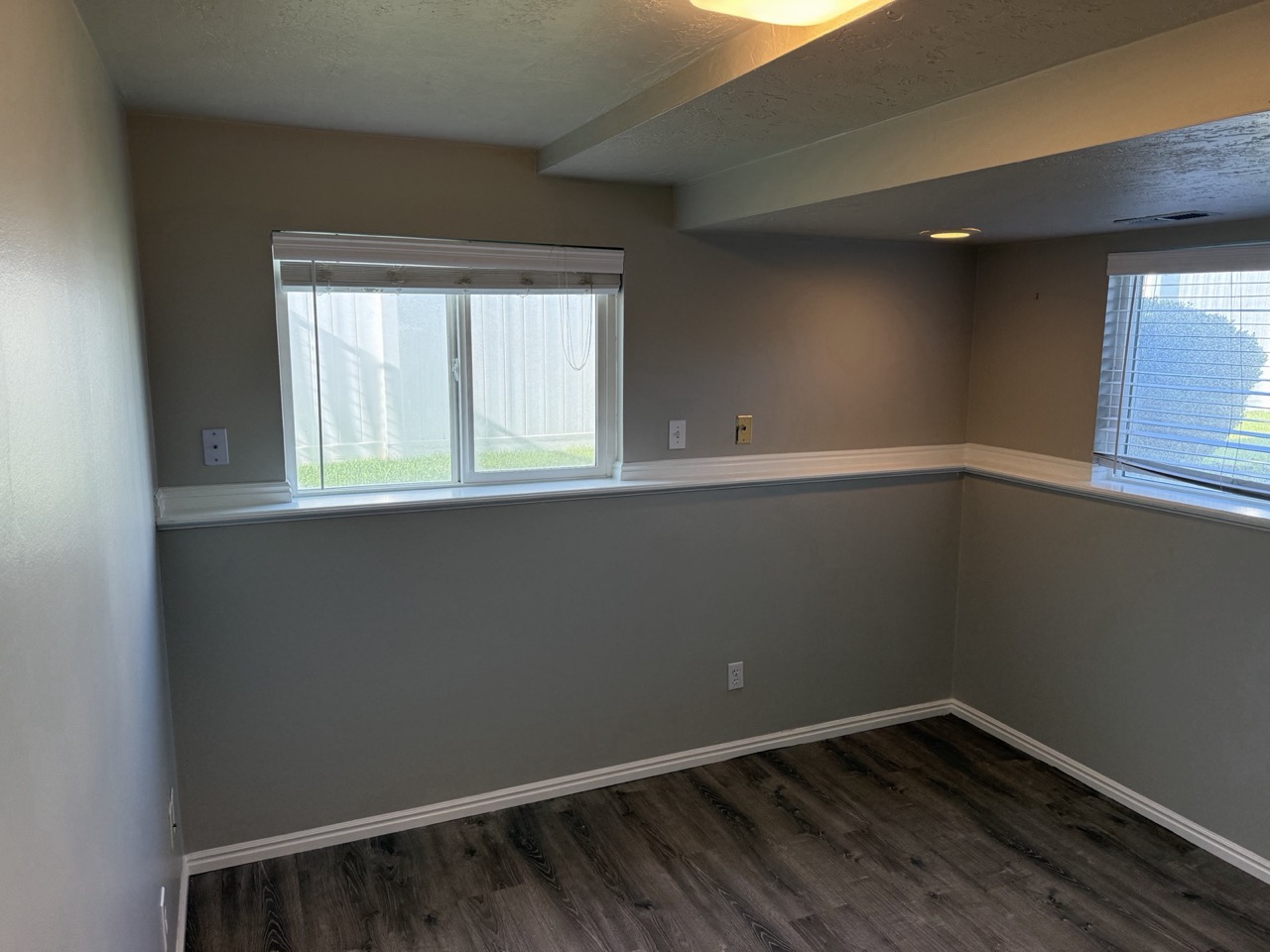 Basement room with two-tone taupe and gray walls and white trim