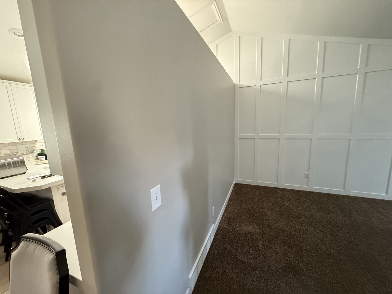 Painted board-and-batten paneling and gray walls next to a kitchen
